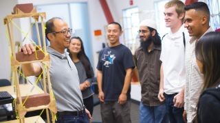 A professor talking with students in a lab.