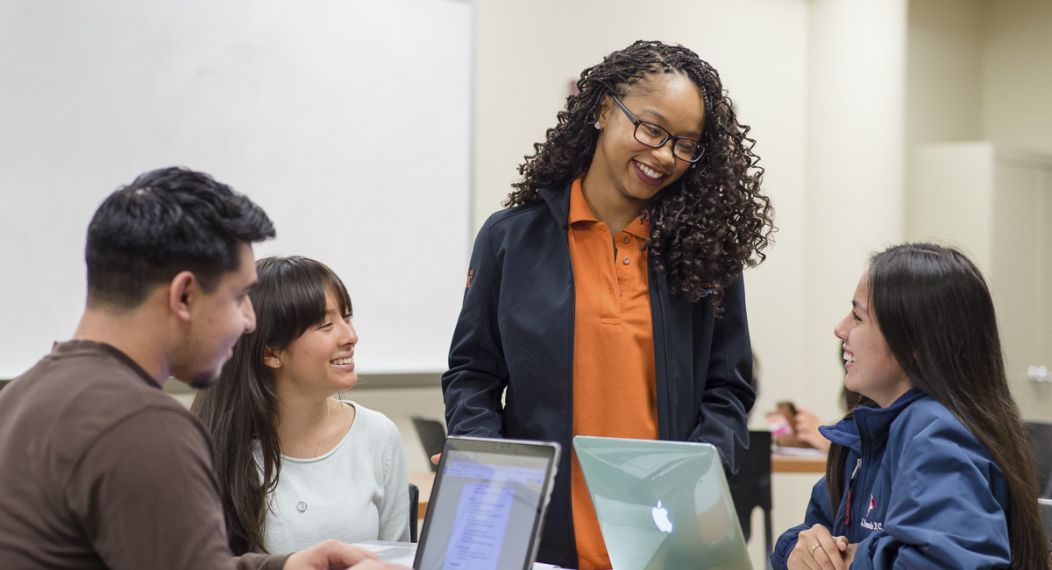 A professor with students using laptops