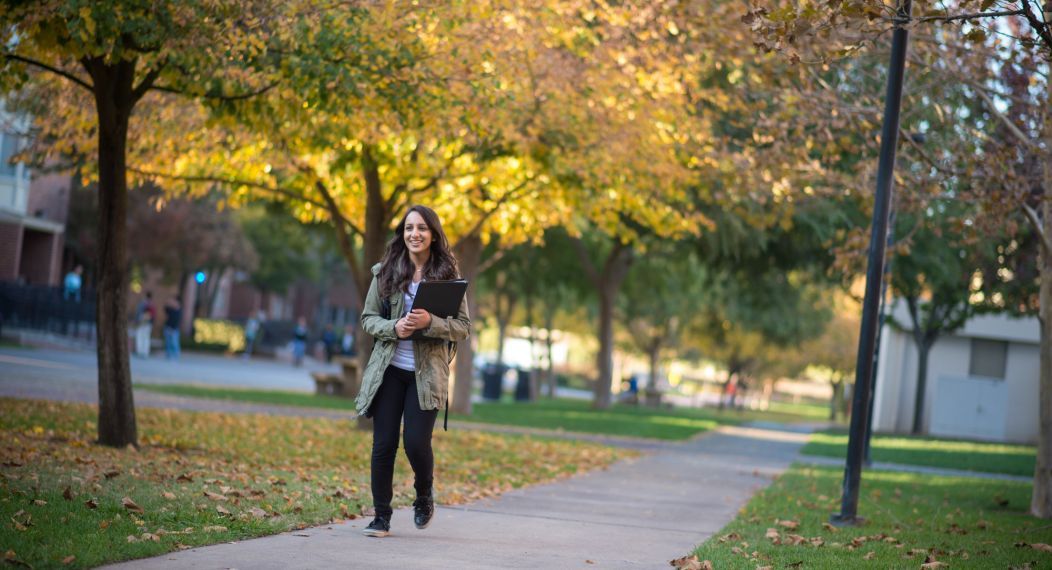 Smiling student walking on campus during fall