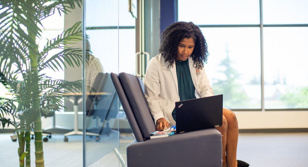 Woman typing on laptop, sitting in a chair