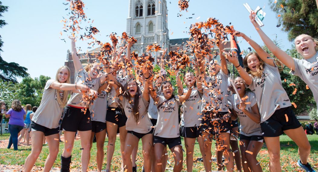 large group of students throwing confetti outdoors