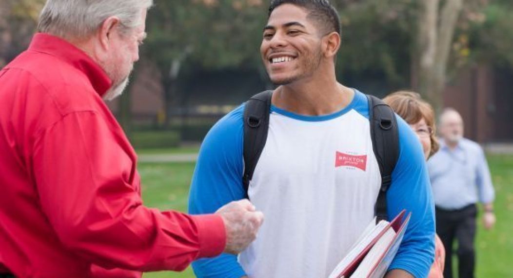 man talking to student carrying books