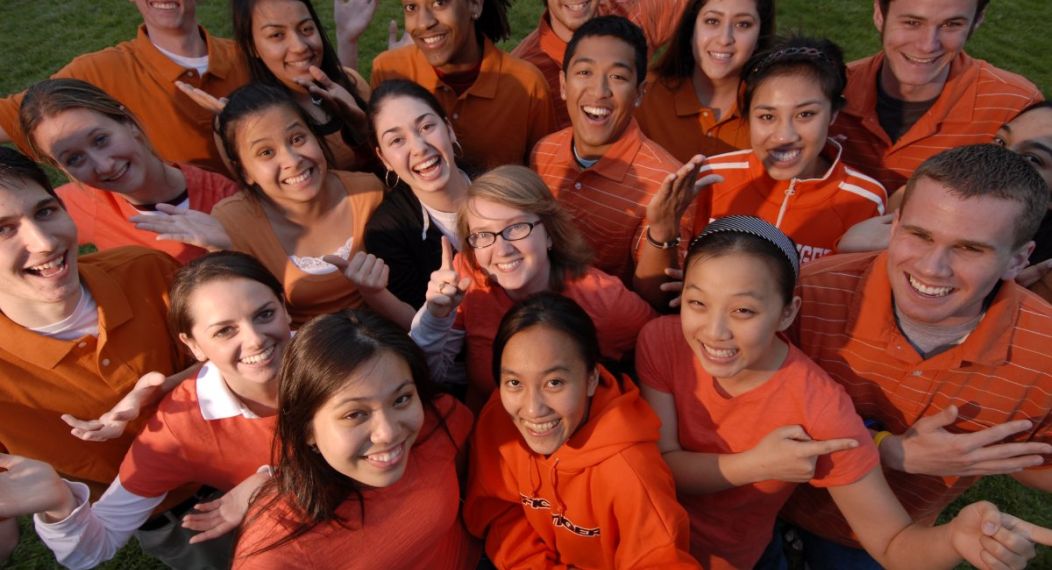 many students smiling and wearing orange shirts