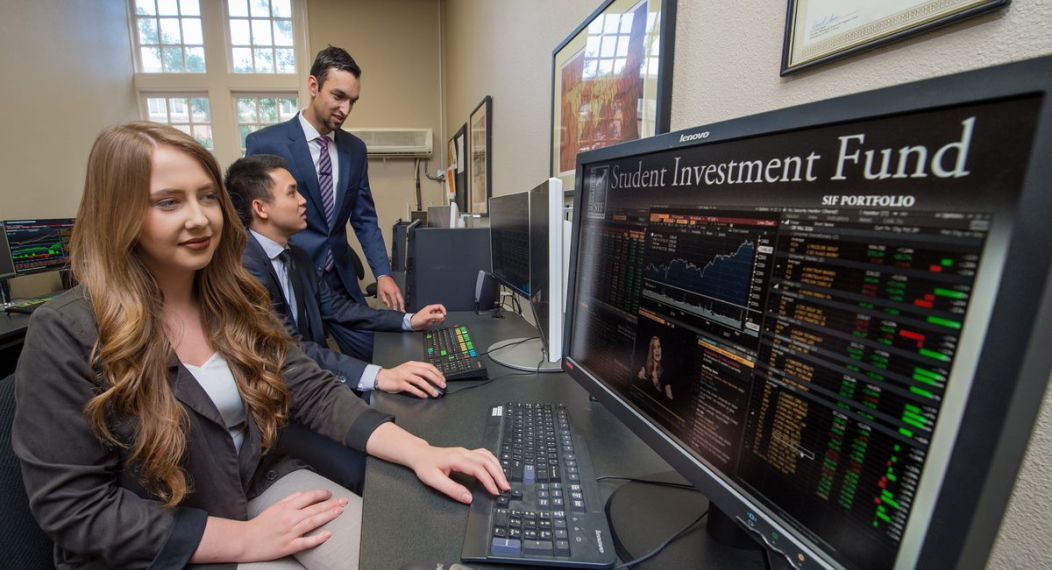 students looking at computer screens indicating financial statistics