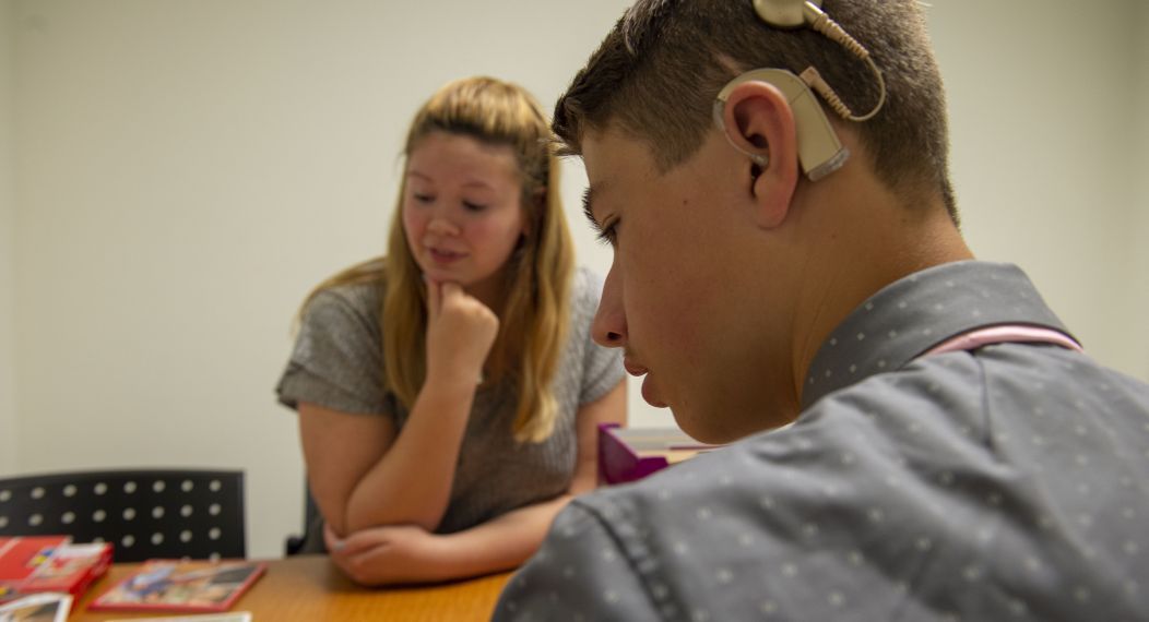student working with someone that has a hearing aid on