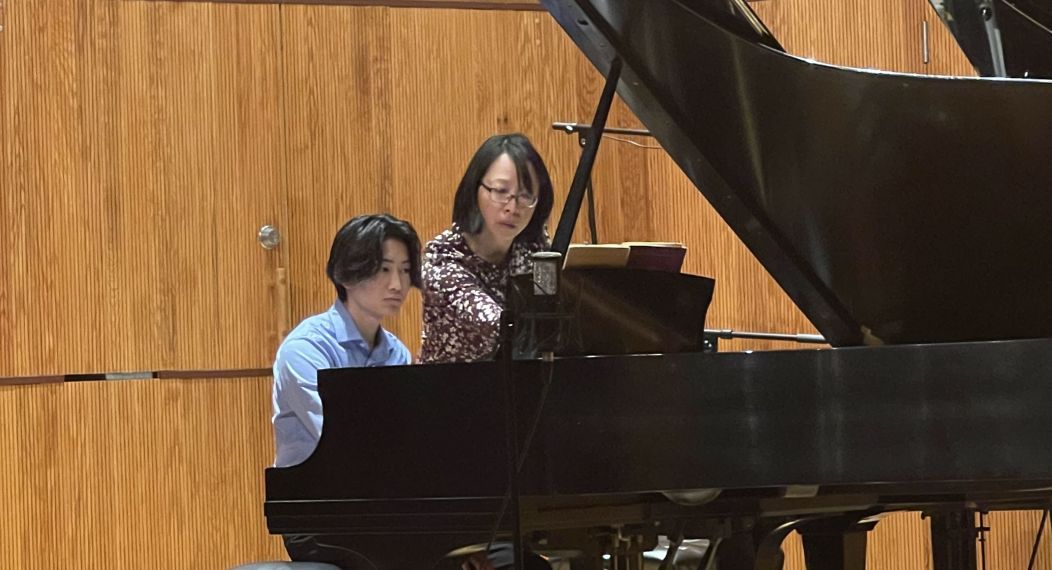 a student and a teacher play piano together