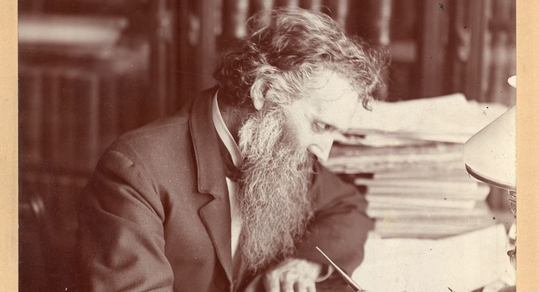 John Muir writing at a desk