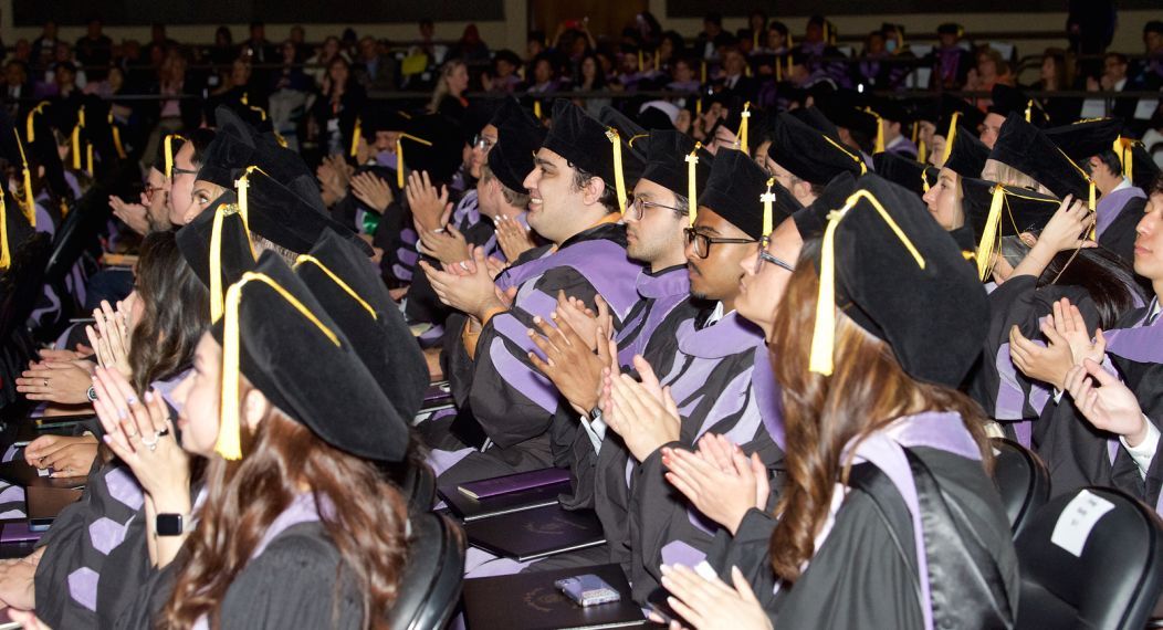 students sitting in their caps and gowns during commencement 2024