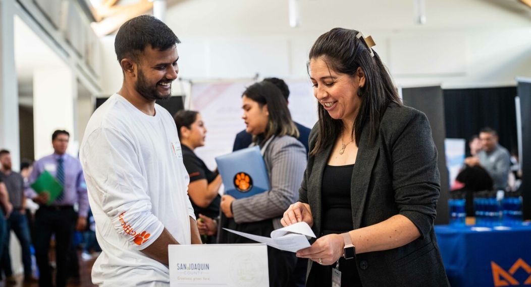 a potential employer looks at a student's resume at a career fair