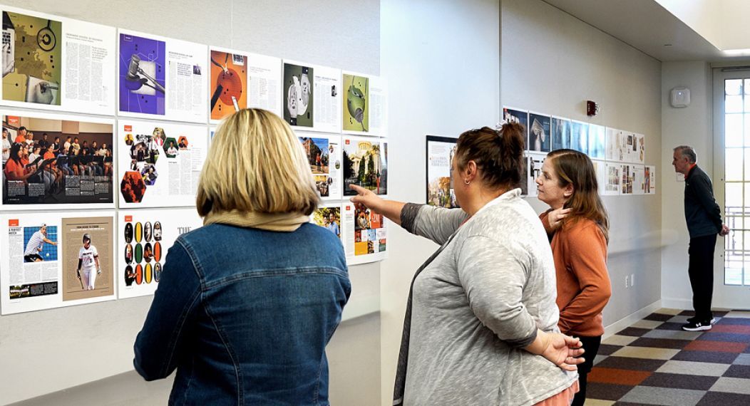 four people looking at spreads from the magazine on a wall