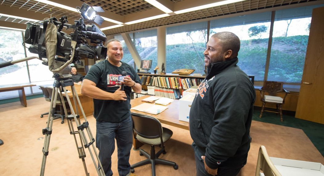 two people stand next to a video camera