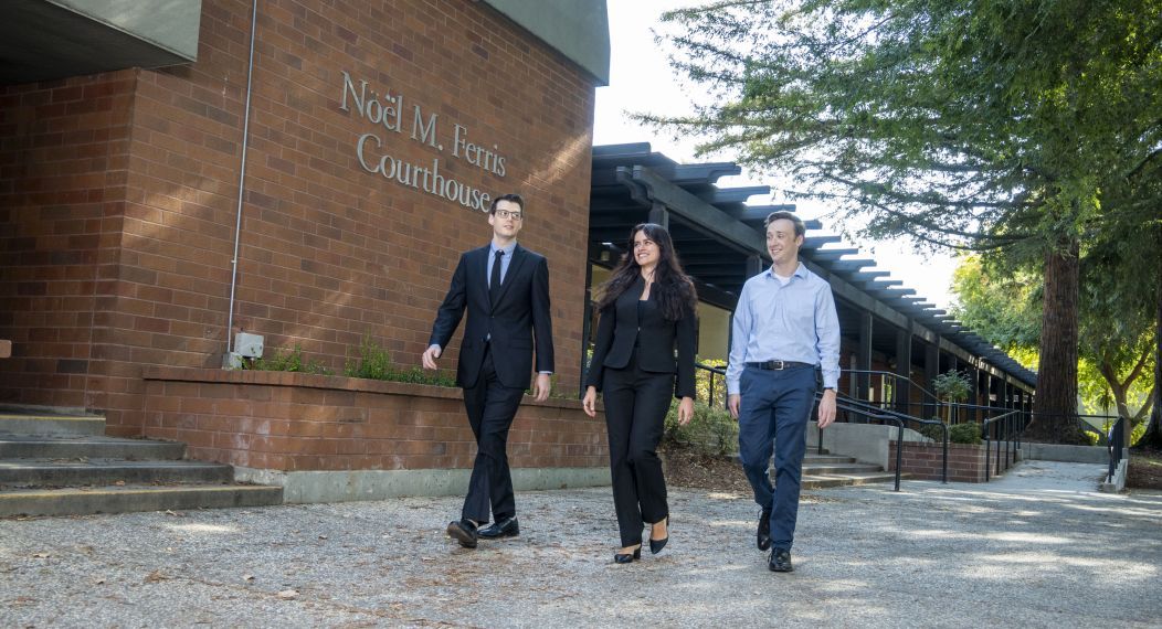 Three individuals walk on campus together