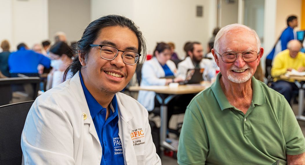 A pharmacy student and health care patient smiling at the camera