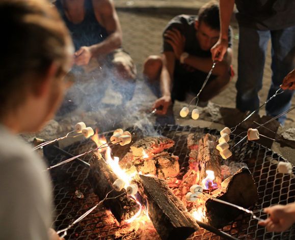 students around a fire pit roasting marshmallows