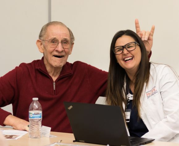 Pharmacy student smiling with elderly patient at clinic