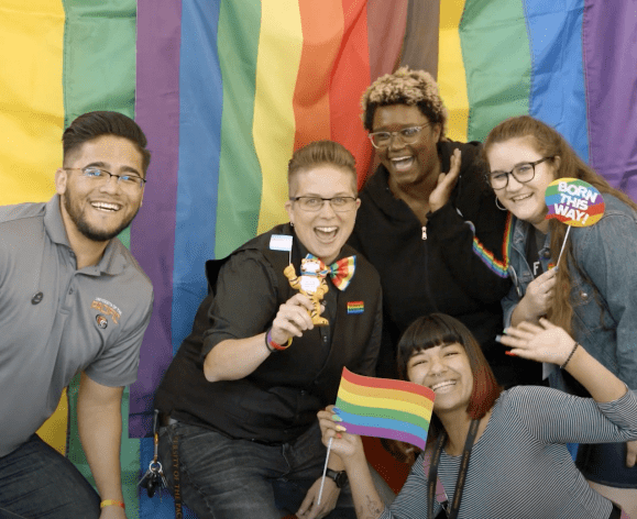 five students in front of rainbow flag