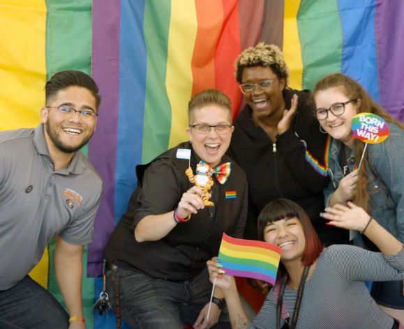 five students in front of rainbow flag