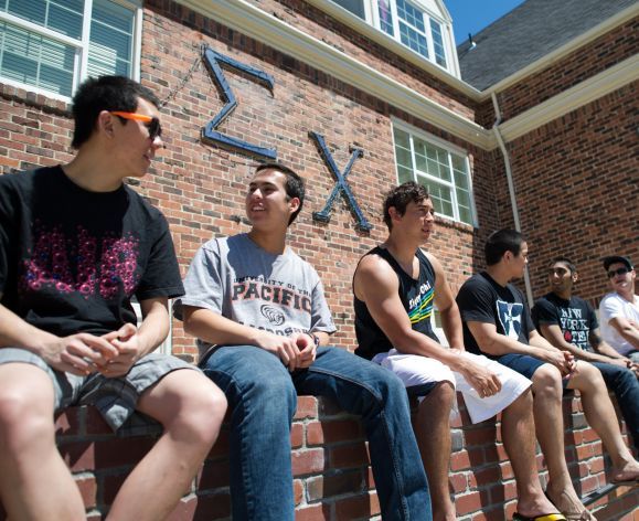 fraternity members hanging out in front of house