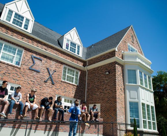 Sigma Chi brothers hanging out in front of house