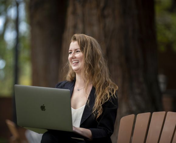 student with laptop sitting on chair outside