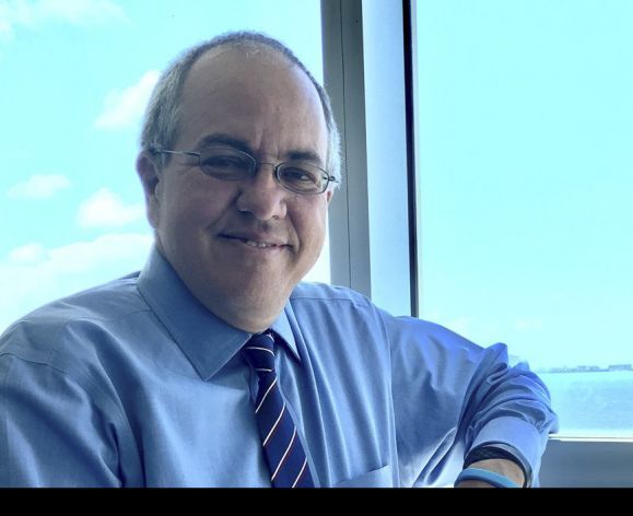 A close up image of a man standing by a window 