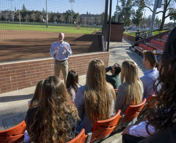 students having a lecture by the baseball fields