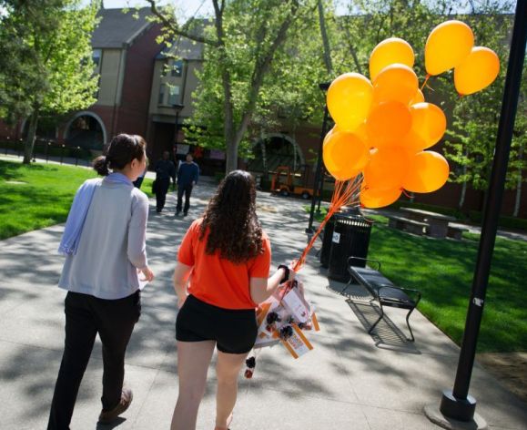 students walking on campus with balloons in the background