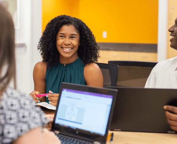 People sitting around a laptop computer and smiling