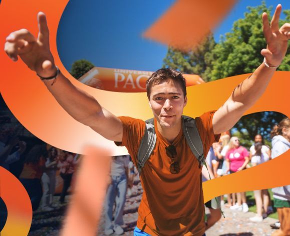 student in an orange tshirt with arms raised