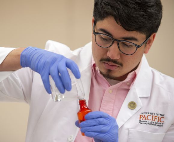 Man wearing white coat working in a compounding lab