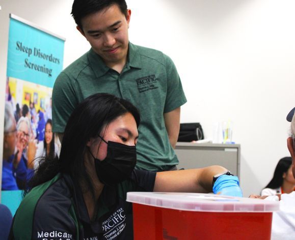 Two pharmacy students with a patient at a health care outreach clinic