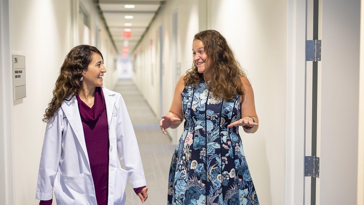 a doctor and a student talking as they walk down a hallway together
