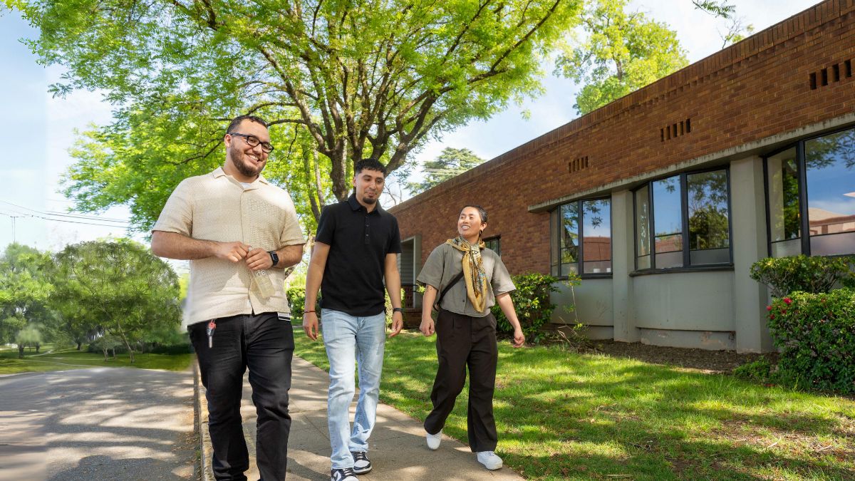 three students walk down the sidewalk together