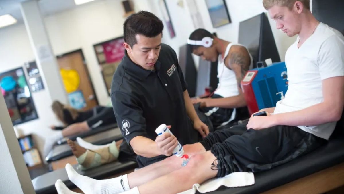 A MSAT student is applying gel to another student's knee in a training simulation