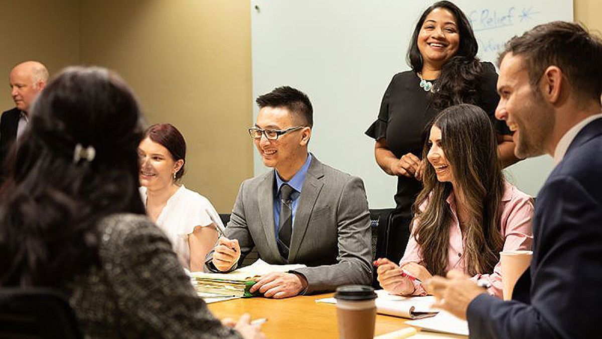 several people sit around a table, smiling and talking