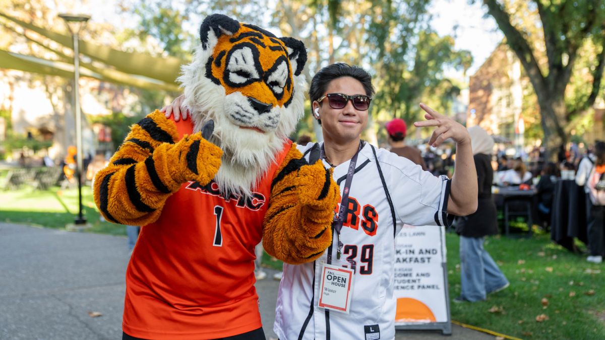 A student in a jersey smiles for a photo with Powercat