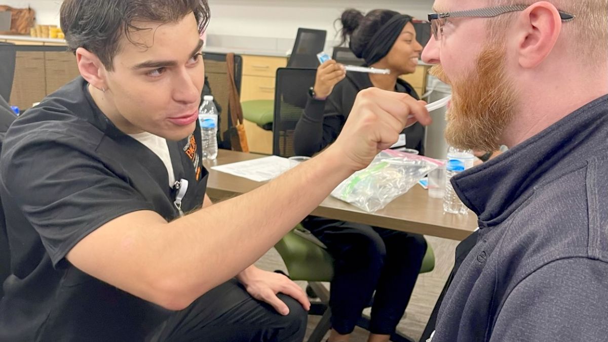 One student is practicing brushing another student's teeth.